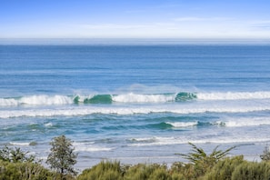 A coastal landscape with waves, vegetation, and a clear sky.