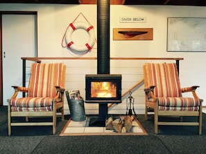 A cozy room with a fireplace, striped chairs, a life preserver, and a map on the wall. - Ocean View - Views Galore (Separation Creek)