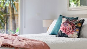 Ein Schlafzimmer mit Bett, Kissen, Decke, Fenster und Tür.