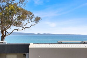 Une vue sur la côte, avec un arbre et un bâtiment doté d’un toit plat.