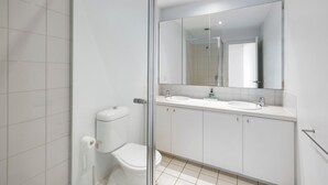 Ein modernes Badezimmer mit Duschkabine aus Glas, Toilette und doppelter Waschtisch.