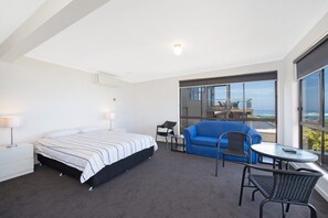Een hotelkamer met een bed, een klein tafeltje, een stoel en een balkon met uitzicht.