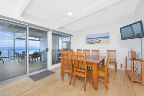 Een modern interieur met een eethoek, een televisie en een schilderij van een strandgezicht.