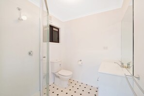 Een badkamer met een toilet, een douche en een wastafel.