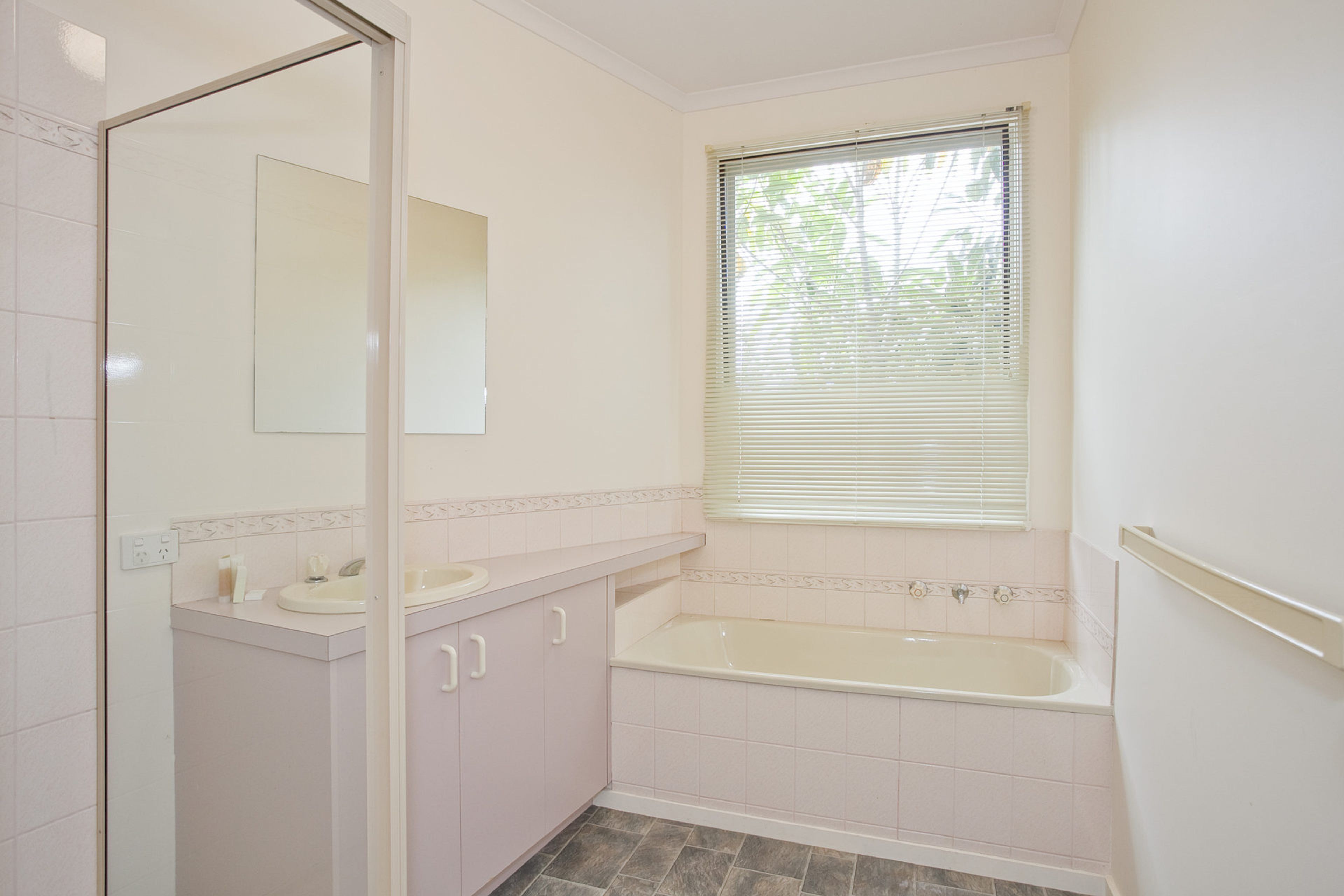 A bathroom with a bathtub, a sink, and a mirror.