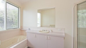 A bathroom with a bathtub, a sink, and a mirror. - Seabreeze - Central Lorne (Lorne)