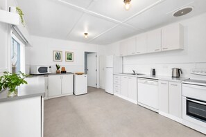 Une cuisine moderne avec des meubles blancs, un four à micro-ondes, un réfrigérateur et un lave-vaisselle.