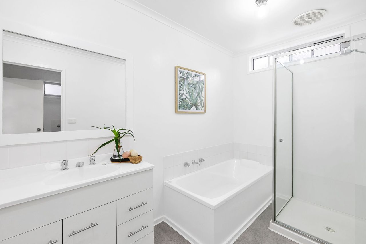 A modern bathroom with a white vanity, a bathtub, and a glass-enclosed shower.