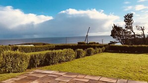 Een geplaveid terras met uitzicht op zee en een heldere lucht.