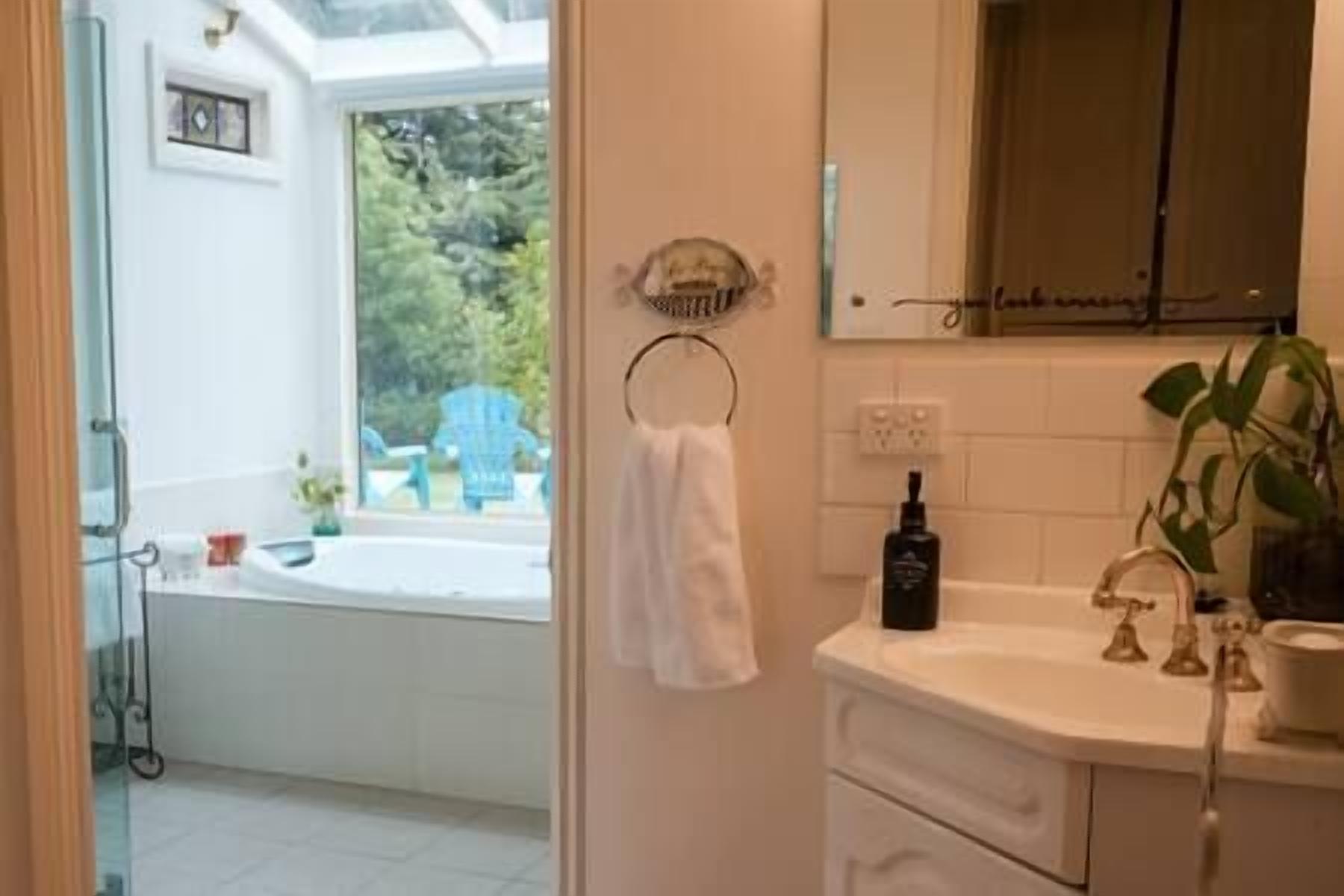A bathroom with a bathtub, a sink, and a window with a view of greenery outside.
