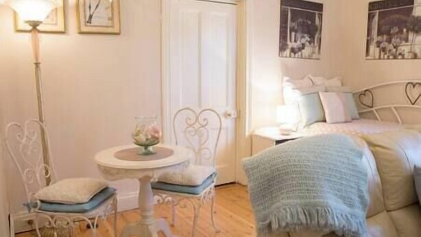 A bedroom with a bed, a bedside table, a lamp, and a chair. - Azalea Cedar-Rose Villa (Lyndoch)