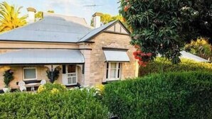 A two-story house with a sloped roof, a front porch, and a well-maintained garden. - Azalea Cedar-Rose Villa (Lyndoch)