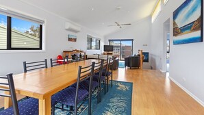 A spacious dining area with a long wooden table, multiple chairs, and a view of the outdoors through large windows.