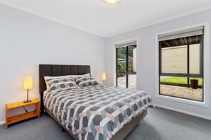 A bedroom with a bed, bedside lamps, a window, and a view of the outside.