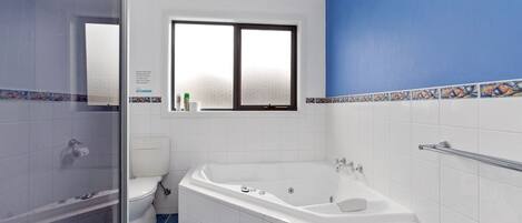 A bathroom with a bathtub, toilet, and a shower area.