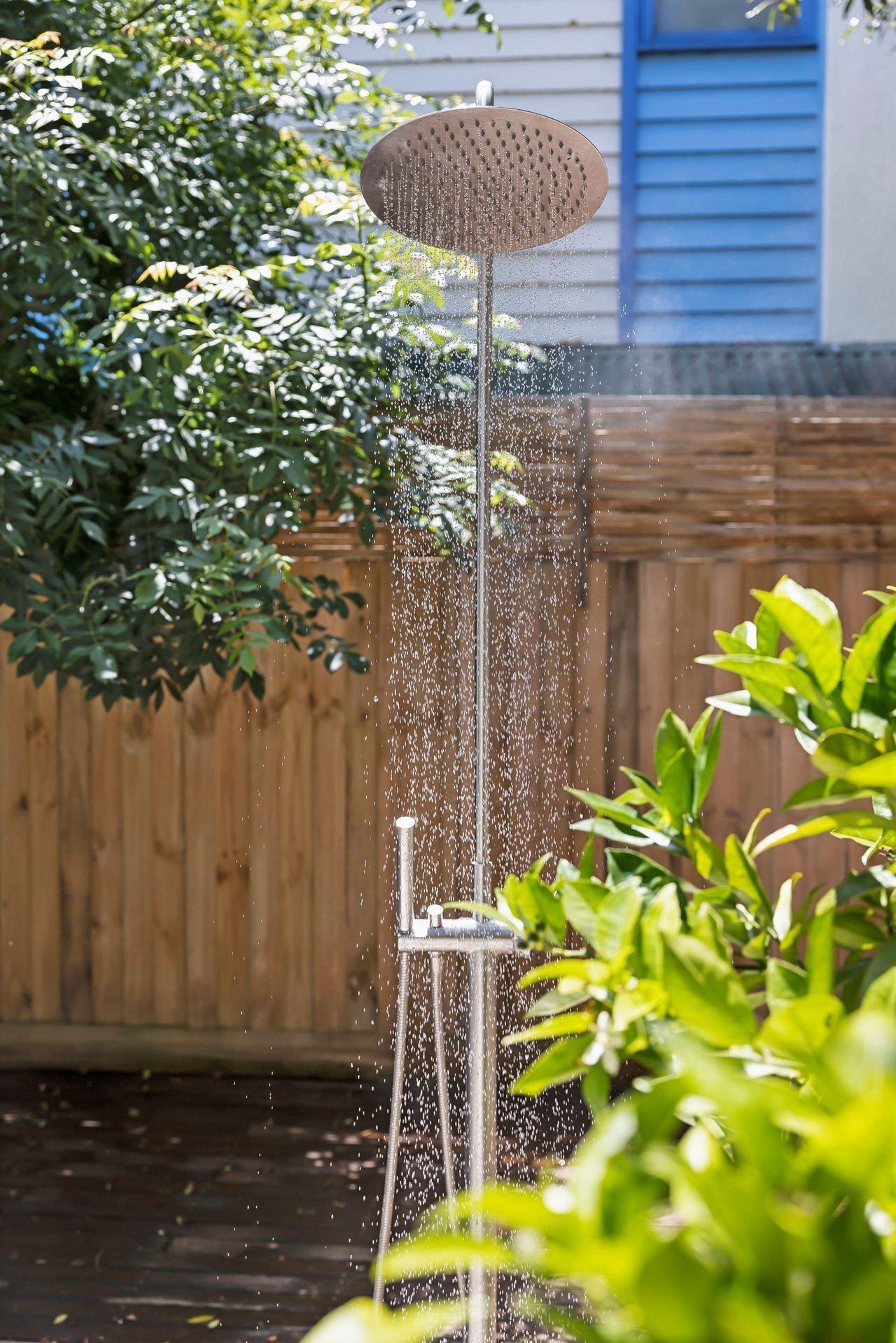 A garden with a water feature, including a metal structure with a circular top and a vertical pole.