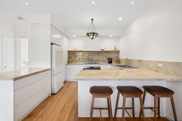 A modern kitchen with white cabinetry, a marble countertop, and a built-in oven.