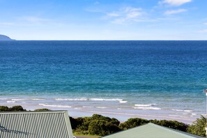 A coastal view with a clear sky, a calm sea, and a distant landmass. - Otway Views (Skenes Creek)