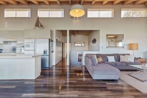 A spacious living area with a kitchen, a dining area, and a large window providing natural light.