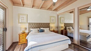 Ein Schlafzimmer mit einem großen Bett, einem Holzkopfende, Nachttischen mit Lampen und gerahmten Bildern an der Wand.