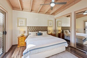 Ein Schlafzimmer mit einem großen Bett, einem Holzkopfende, Nachttischen mit Lampen und gerahmten Bildern an der Wand.