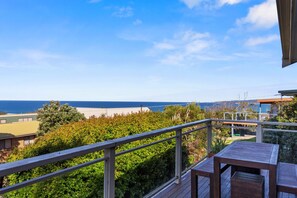 A balcony with a view of the beach and ocean.