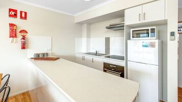 A modern kitchen with white cabinetry, a stainless steel sink, and a white refrigerator.