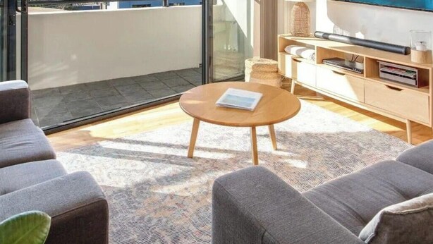 A modern living room with a sofa set, a coffee table, a TV, and a sliding glass door leading to a balcony. - Husky Oasis by Book Jervis Bay - Centre OF Huskisson - (Huskisson)