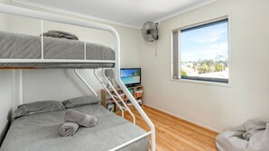 A bunk bed room with a TV, a fan, and a window with a view of a beach. - Husky Oasis by Book Jervis Bay - Centre OF Huskisson - (Huskisson)