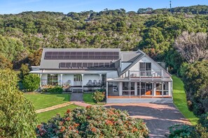 A modern house with a large deck, a covered patio, and a well-maintained garden. - The Great Escape (Marengo)