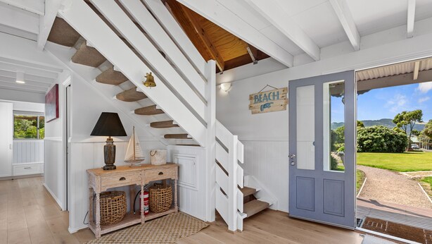 Eine Holztreppe, eine Tür mit dem Schild 'BEACH' und Blick ins Freie.