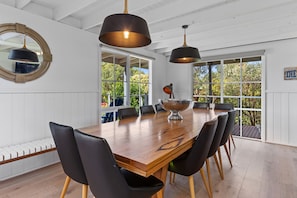 A dining area with a wooden table, black chairs, and pendant lighting.
