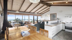 A spacious kitchen with a large island, wooden beams on the ceiling, and a view of the ocean through large windows. - Seamoon - Apollo Bay (Apollo Bay)