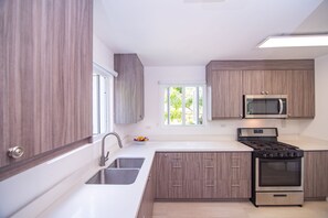 Una cocina moderna con armarios de madera, un lavamanos de acero inoxidable, una estufa a gas y un microondas.