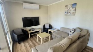 A living room with a flat-screen TV, a sofa, a chair, and a coffee table.