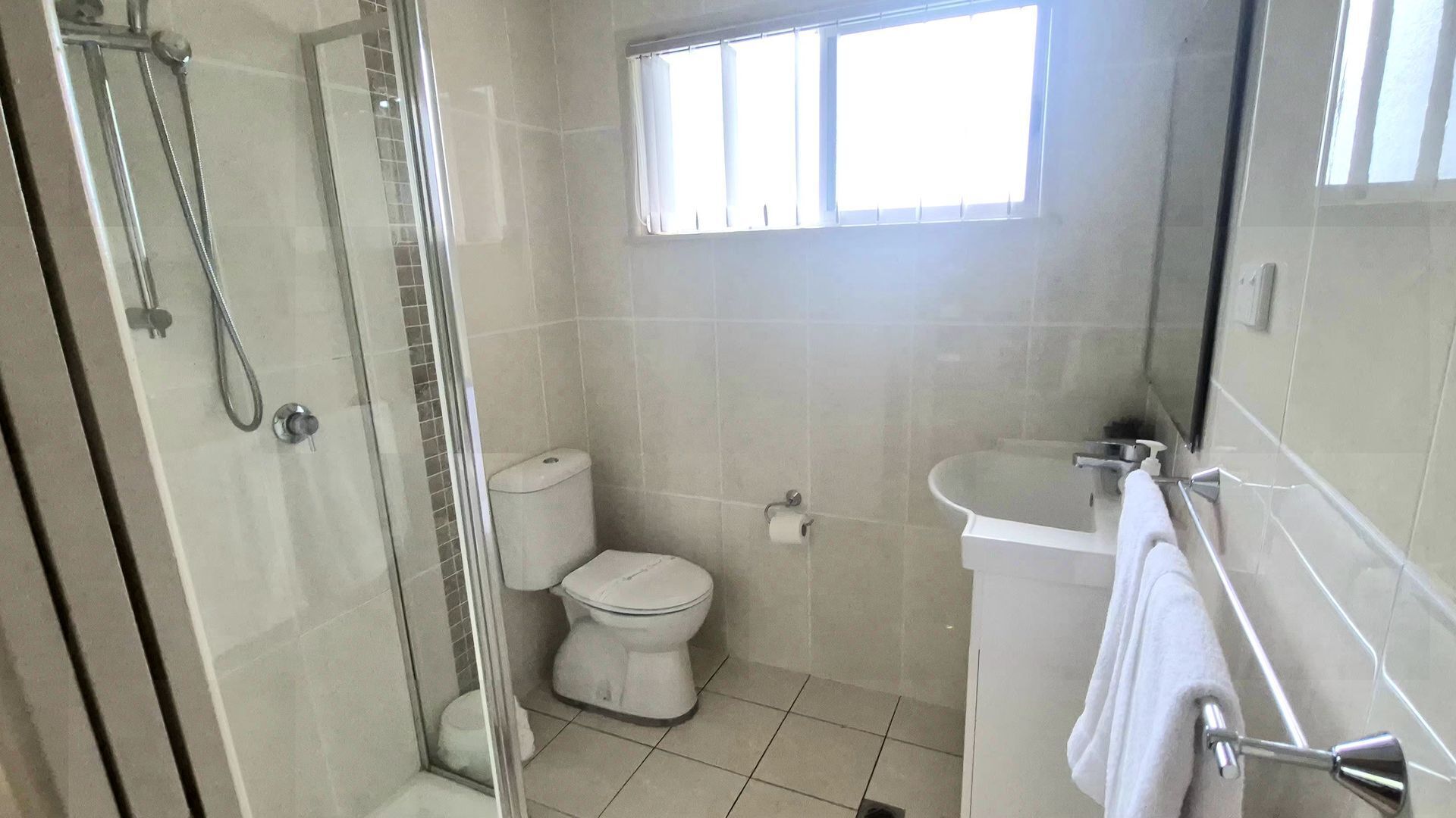 A bathroom with a toilet, shower, and sink.