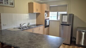 A compact kitchen with a sink, stainless steel appliances, and wooden cabinets.