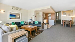 En moderne stue med sofa, sofabord og et spiseområde med stole og bord.