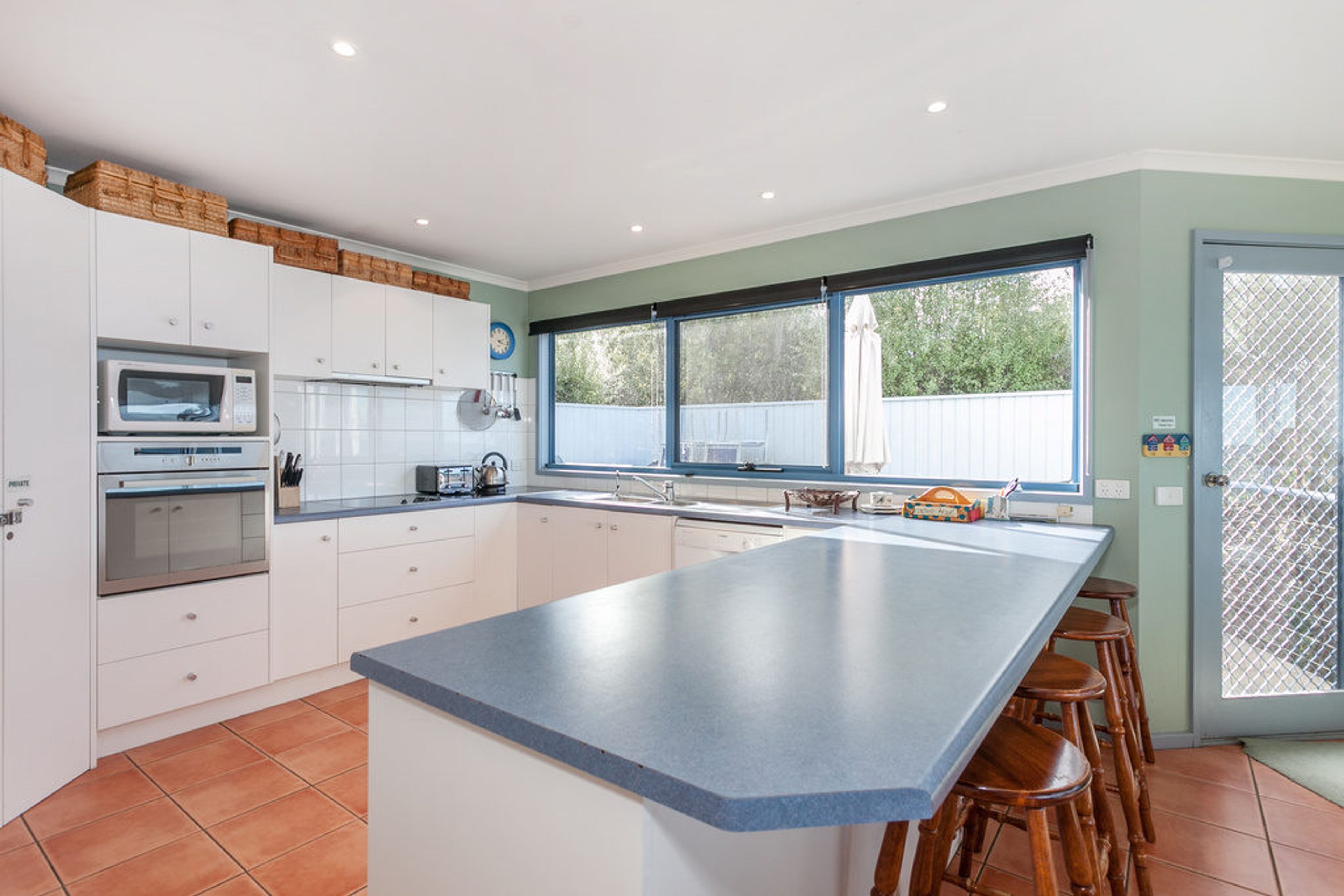 Una cocina moderna con armarios blancos, una isla grande y vistas al exterior.