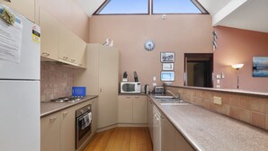 A kitchen with a microwave, toaster, sink, and wooden flooring.