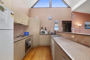 A kitchen with a microwave, toaster, sink, and wooden flooring.