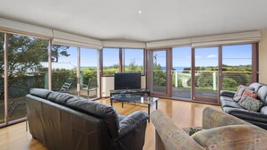 A spacious living room with a large TV, leather sofas, and a glass coffee table.
