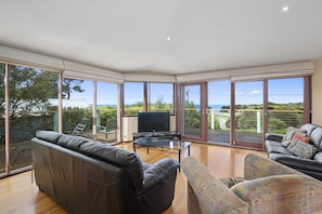 A spacious living room with a large TV, leather sofas, and a glass coffee table.