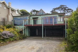 Une maison à deux étages avec un garage fermé et une véranda à l’avant.