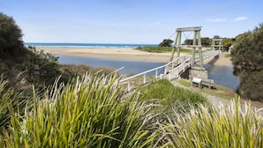 A wooden bridge over a river leading to a beach.