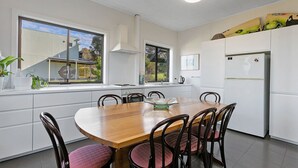 A modern kitchen with a wooden dining table, white cabinets, and a built-in oven.