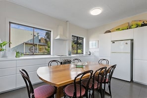 A modern kitchen with a wooden dining table, white cabinets, and a built-in oven.