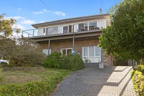A two-story building with a balcony, a paved driveway, and a sign indicating a parking area. - Mirimar (Skenes Creek, Apollo Bay)