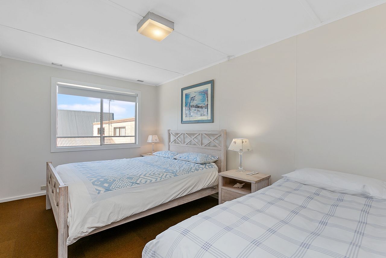Une chambre avec deux lits, une fenêtre donnant sur un beau paysage, une table de chevet avec une lampe et un tableau encadré au mur.