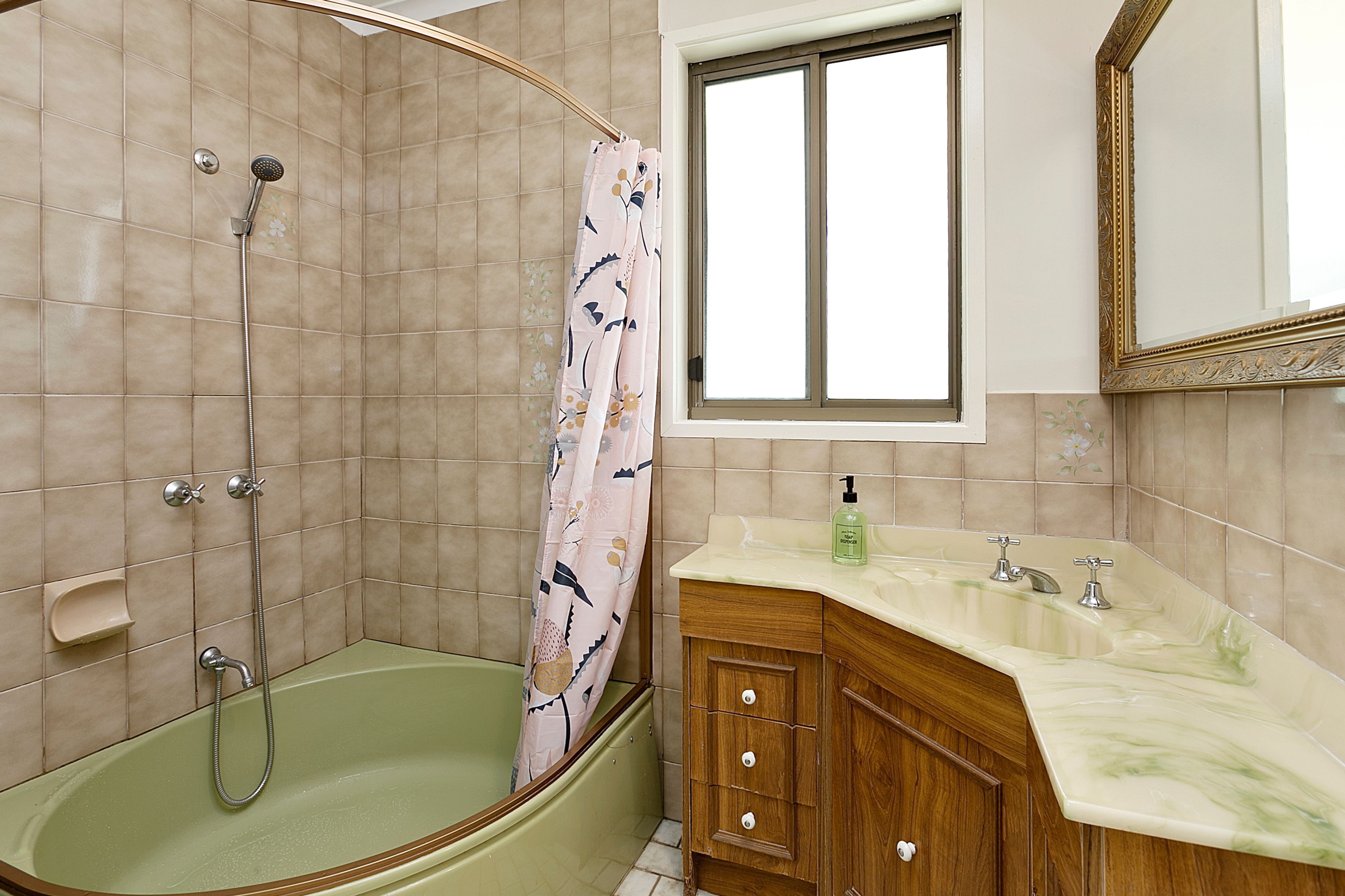 Un baño con ducha, bañera, tocador con espejo y ventana.